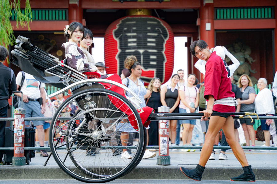 雷門前でポーズを取る人力車の俥夫と着物のお客様
